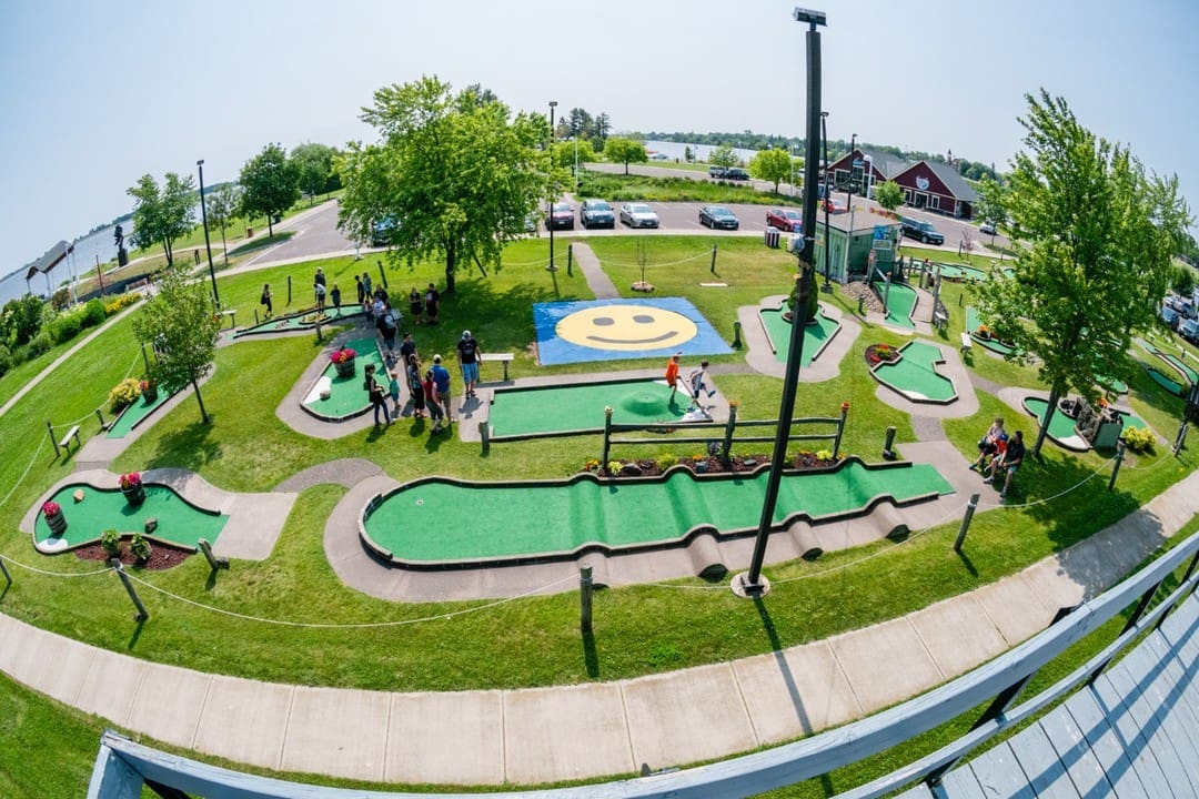 A group of people playing mini golf on the grass.