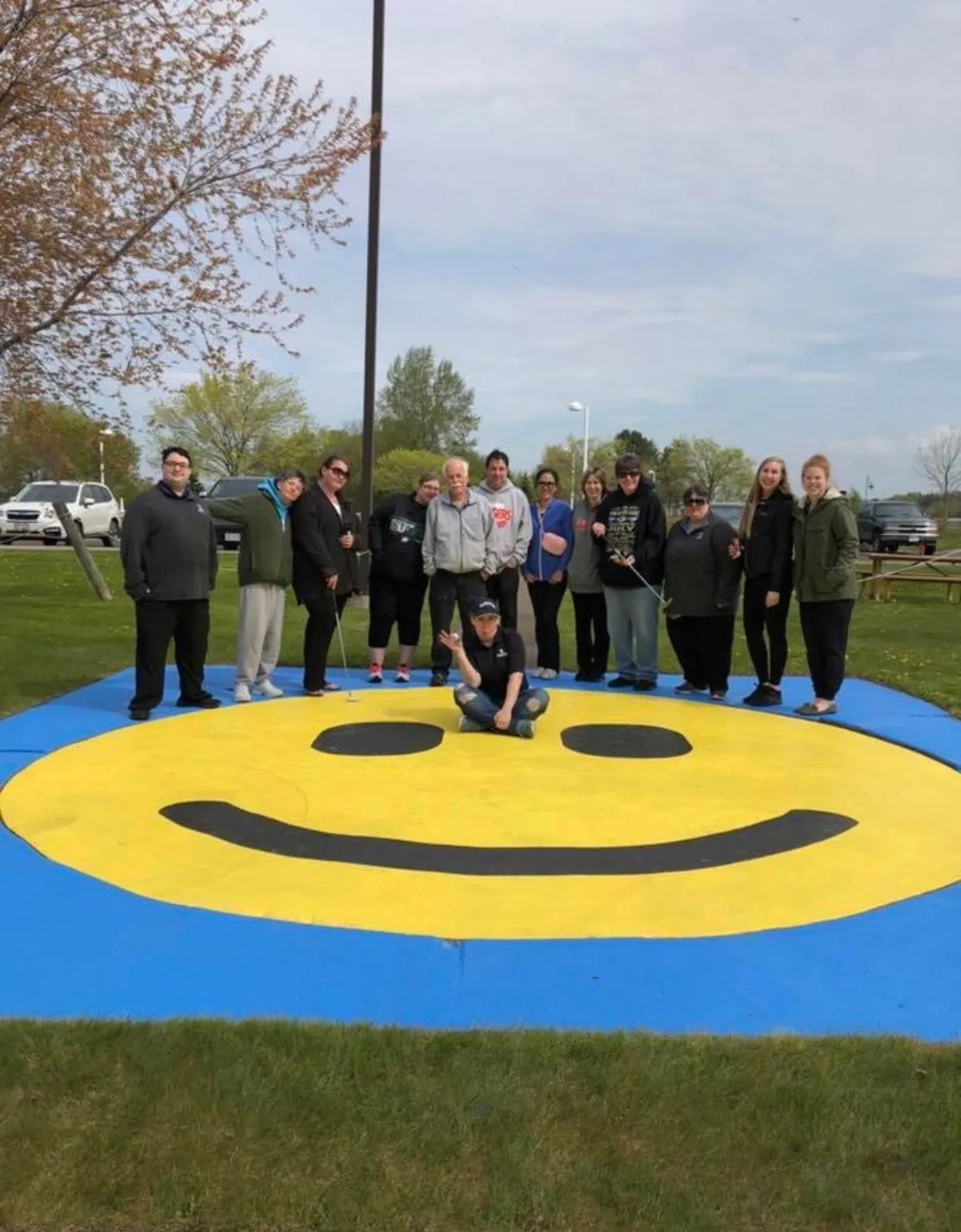 A group of people standing around a smiley face.